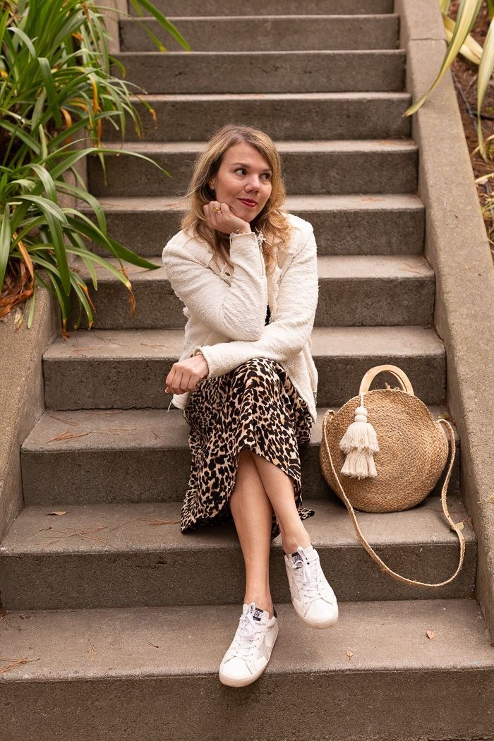 White sneakers styled with a leopard skirt on stone steps