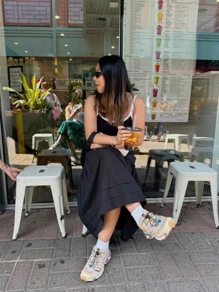 Neutral sneakers styled with a black dress at a café